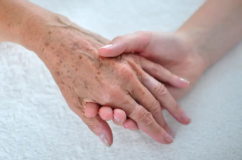 person-holding-an-old-womans-hand-2023-11-27-05-09-43-utc-scaled